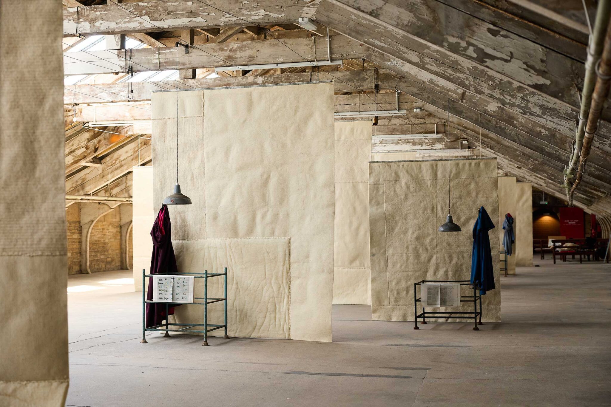 We Will Sing — hanging fabric banners and garment rails inside the venue, Ann Hamilton / BD25 2025. Photo: David Lindsay